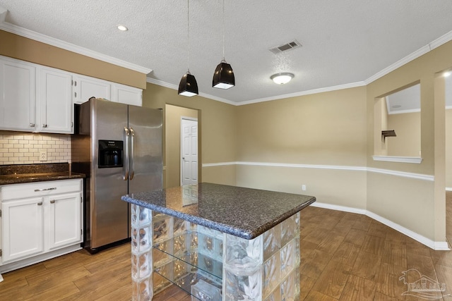 kitchen featuring white cabinets, stainless steel fridge, dark stone countertops, and a center island