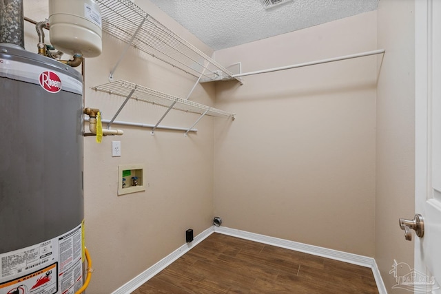 washroom featuring dark hardwood / wood-style floors, gas water heater, washer hookup, a textured ceiling, and hookup for an electric dryer