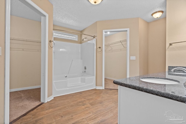 bathroom featuring vanity, a textured ceiling, and washtub / shower combination