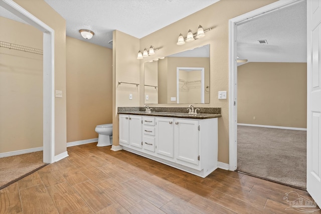 bathroom featuring a textured ceiling, toilet, and vanity