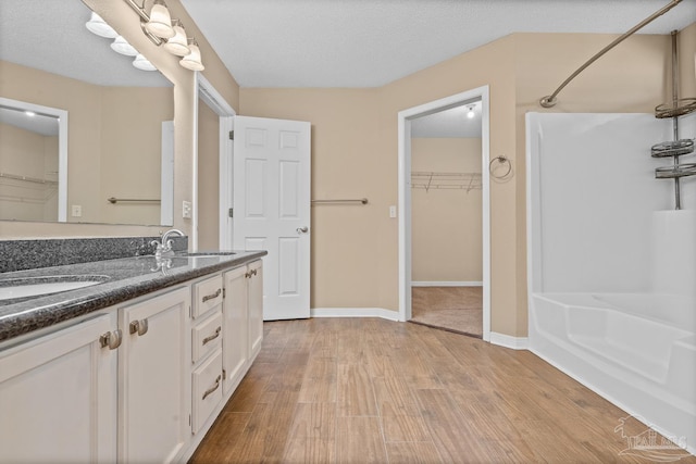 bathroom with a textured ceiling, a shower, hardwood / wood-style floors, and vanity