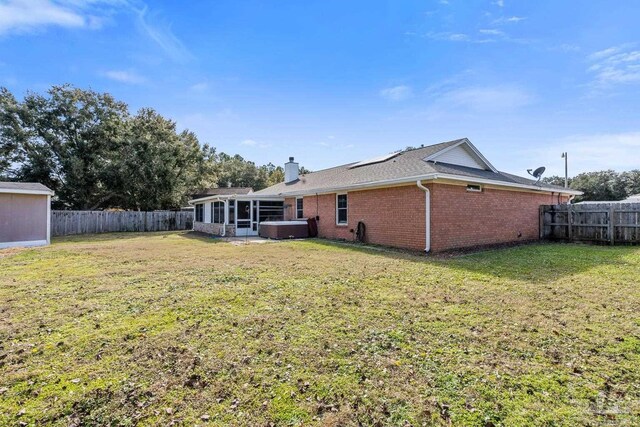 back of property with a hot tub and a yard