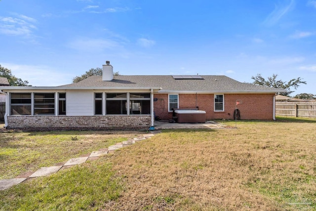 back of house with solar panels, a hot tub, and a yard