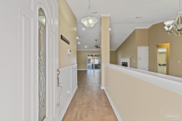 corridor with vaulted ceiling, an inviting chandelier, crown molding, and hardwood / wood-style floors