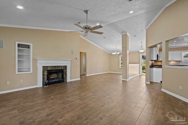 unfurnished living room with vaulted ceiling, ceiling fan with notable chandelier, ornamental molding, and a textured ceiling