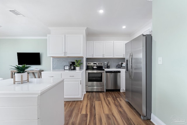 kitchen featuring crown molding, dark wood-type flooring, appliances with stainless steel finishes, backsplash, and white cabinets