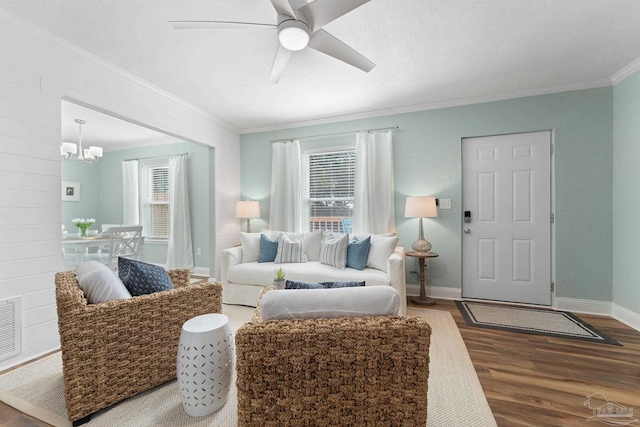 living room with crown molding, hardwood / wood-style flooring, ceiling fan with notable chandelier, and a textured ceiling