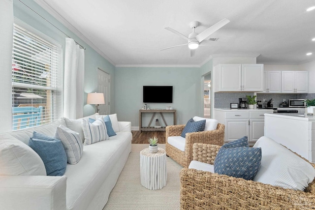 living room with ceiling fan, ornamental molding, and light hardwood / wood-style flooring