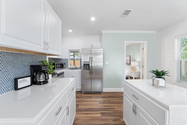 kitchen featuring white cabinetry, stainless steel appliances, a center island, and tasteful backsplash