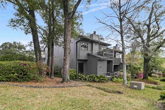 rear view of house with a balcony and a yard