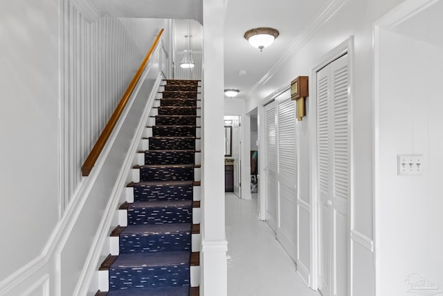 stairway with tile patterned floors and crown molding