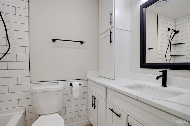 full bathroom featuring tiled shower / bath, vanity, tile walls, and toilet