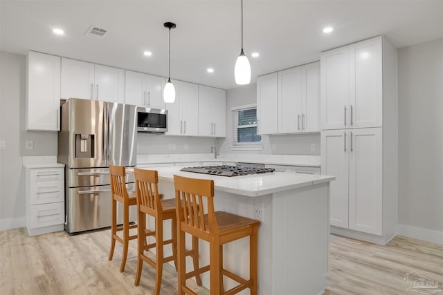 kitchen with a center island, white cabinets, light wood-type flooring, and appliances with stainless steel finishes