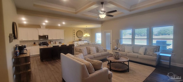 living room with coffered ceiling, beamed ceiling, ornamental molding, ceiling fan with notable chandelier, and dark hardwood / wood-style flooring