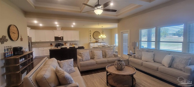 living room featuring light hardwood / wood-style floors, ornamental molding, a tray ceiling, and ceiling fan with notable chandelier