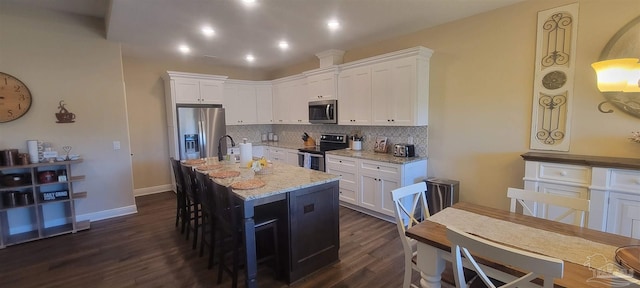 kitchen featuring light stone counters, stainless steel appliances, dark hardwood / wood-style floors, and white cabinets