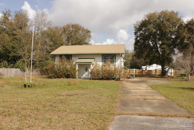 view of front facade with metal roof, a front yard, and fence