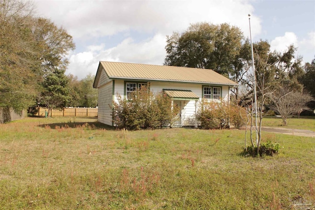 view of front of home with metal roof, a front yard, and fence