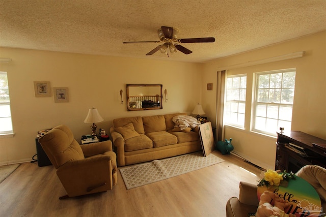 living area with a textured ceiling, wood finished floors, baseboards, and ceiling fan