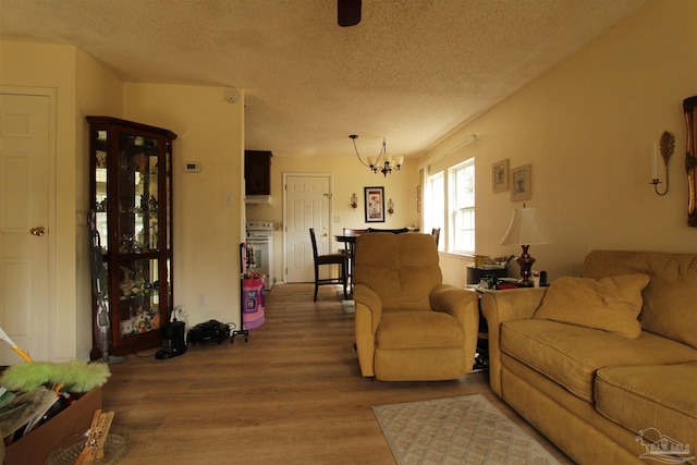 living room featuring a chandelier, a textured ceiling, and wood finished floors