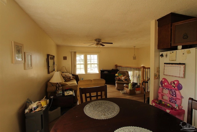 dining area with a textured ceiling, a ceiling fan, and light wood finished floors