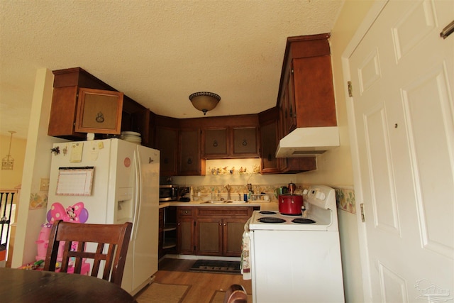 kitchen featuring a sink, a textured ceiling, dark wood-style floors, white appliances, and light countertops