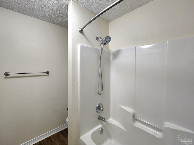 bathroom featuring toilet, hardwood / wood-style flooring, a textured ceiling, and shower / tub combination