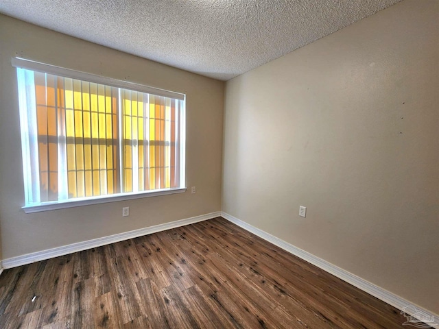 unfurnished room featuring dark wood-type flooring and a textured ceiling