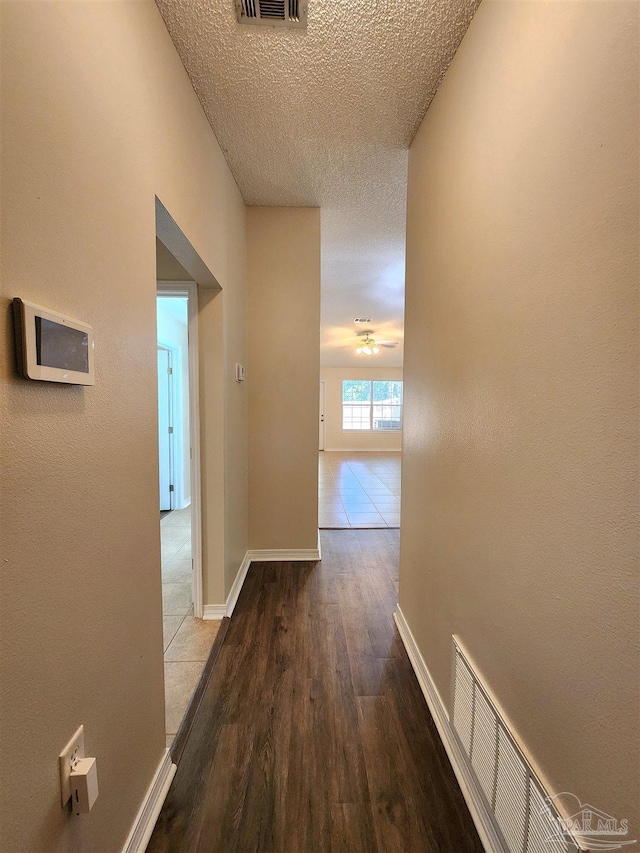 hallway with hardwood / wood-style floors and a textured ceiling