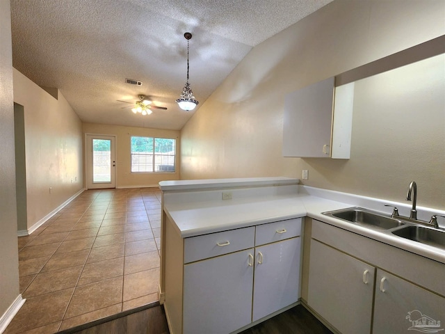 kitchen with hanging light fixtures, kitchen peninsula, sink, a textured ceiling, and ceiling fan