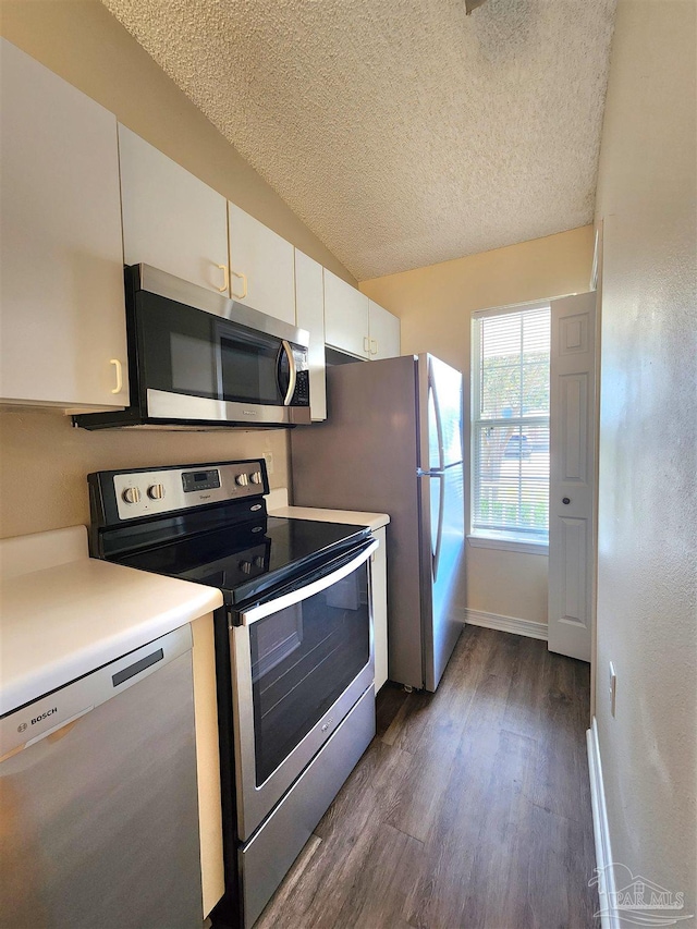 kitchen with a textured ceiling, white cabinetry, stainless steel appliances, and dark hardwood / wood-style flooring