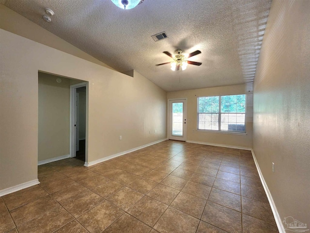 empty room with a textured ceiling, tile patterned flooring, vaulted ceiling, and ceiling fan