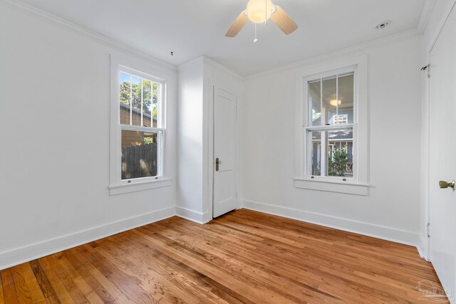 empty room featuring light wood-style floors, ceiling fan, baseboards, and ornamental molding