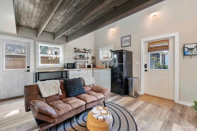 living area featuring light wood finished floors, plenty of natural light, and beamed ceiling