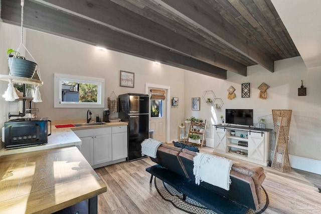 living room with a toaster, beamed ceiling, and light wood-style flooring