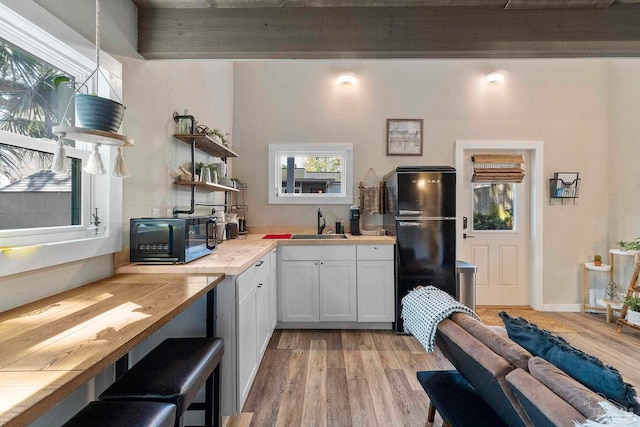 kitchen with open shelves, freestanding refrigerator, light wood-type flooring, and a healthy amount of sunlight