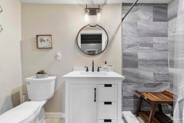 bathroom with toilet, walk in shower, vanity, and baseboards