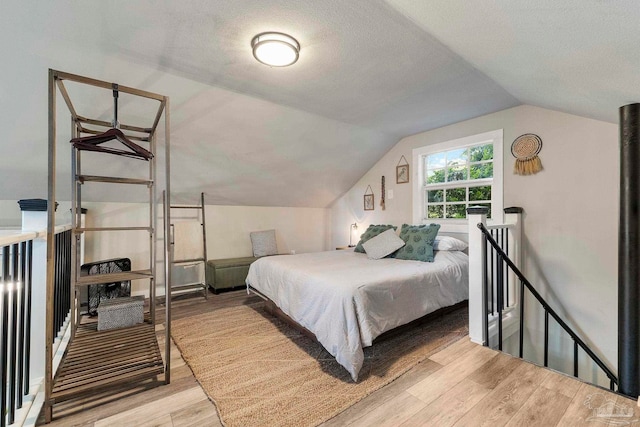 bedroom featuring vaulted ceiling, a textured ceiling, and light wood finished floors