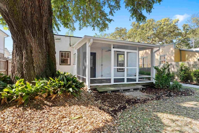 bungalow-style home featuring stucco siding, a sunroom, fence, and ceiling fan