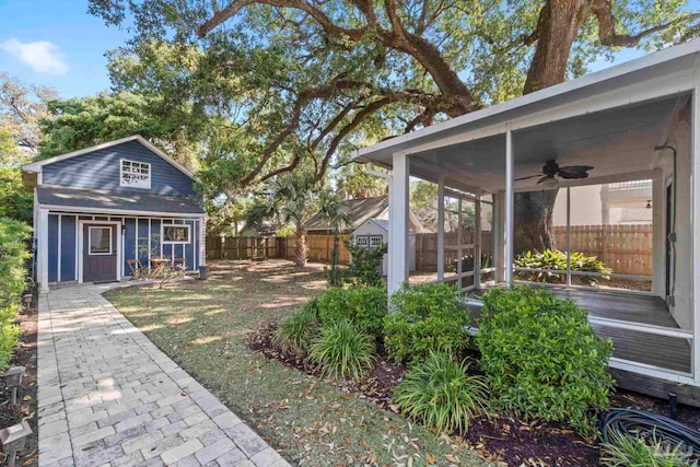 view of yard featuring ceiling fan, a fenced backyard, and an outdoor structure