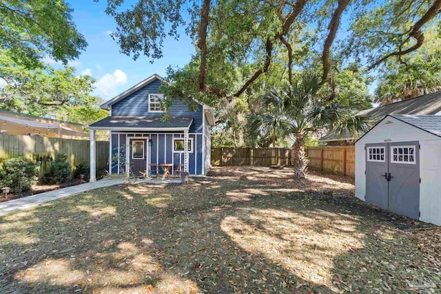 rear view of house featuring a fenced backyard and an outbuilding