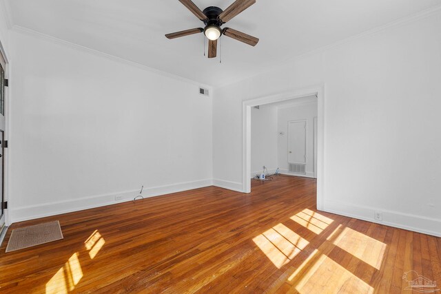 empty room featuring crown molding, visible vents, a ceiling fan, and hardwood / wood-style flooring