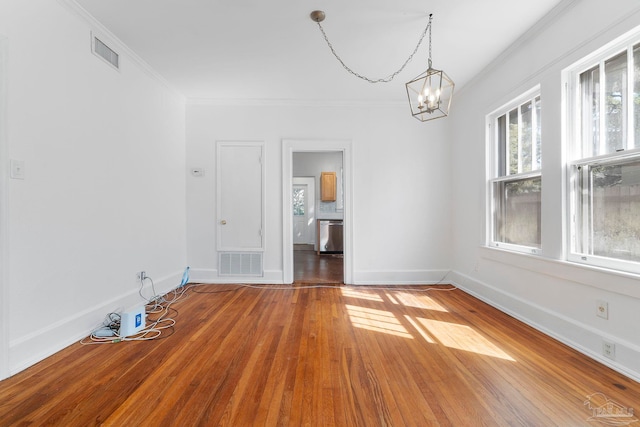 unfurnished dining area with hardwood / wood-style flooring, visible vents, a notable chandelier, and ornamental molding