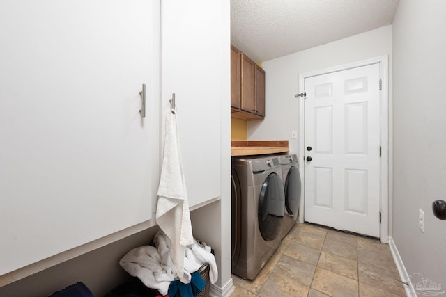 washroom featuring washer and clothes dryer, cabinets, and a textured ceiling