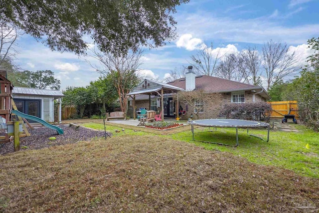 back of house with a trampoline, a patio, a lawn, and a playground