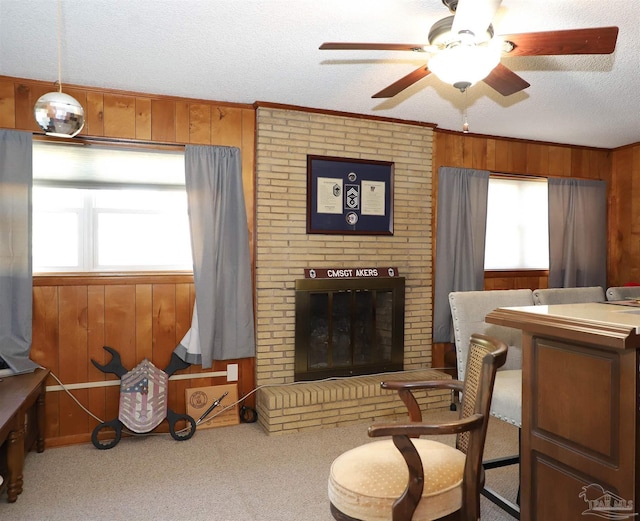 living area with crown molding, carpet floors, a fireplace, a textured ceiling, and wood walls