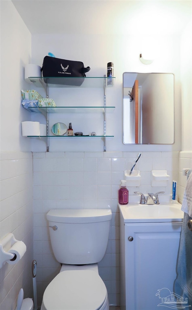 bathroom with vanity, tile walls, and toilet