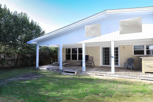 rear view of property with a wooden deck and a lawn