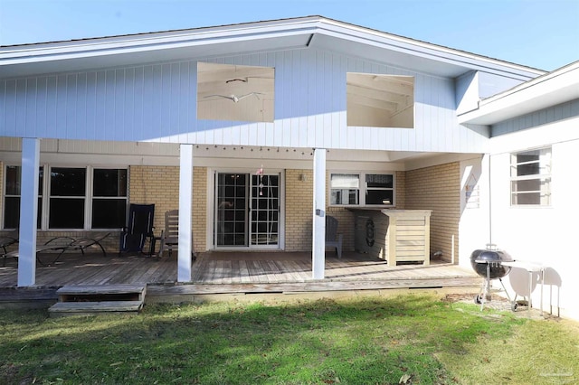 back of property with a wooden deck and a lawn