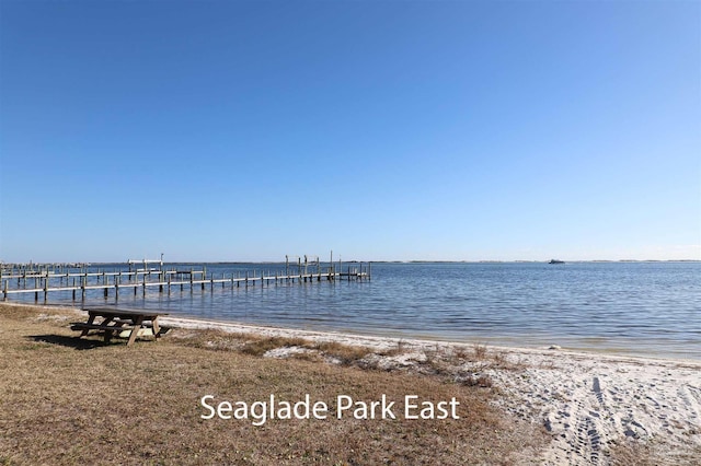 view of dock featuring a water view and a view of the beach